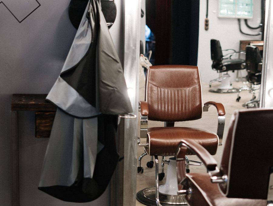 An empty barber chair with a cape hanging beside it