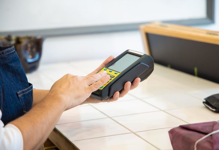 A shop assistant holding a portable card terminal at a counter